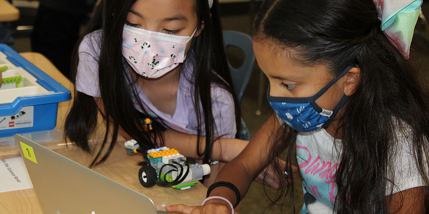 two girls work together on a coding project