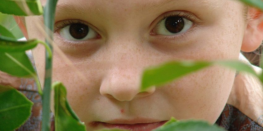 student peeking through leaves