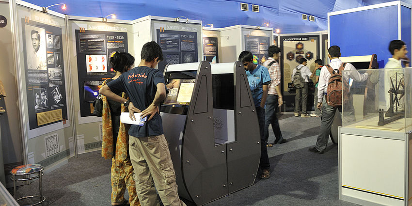 several students with backpacks interacting with technology exhibits