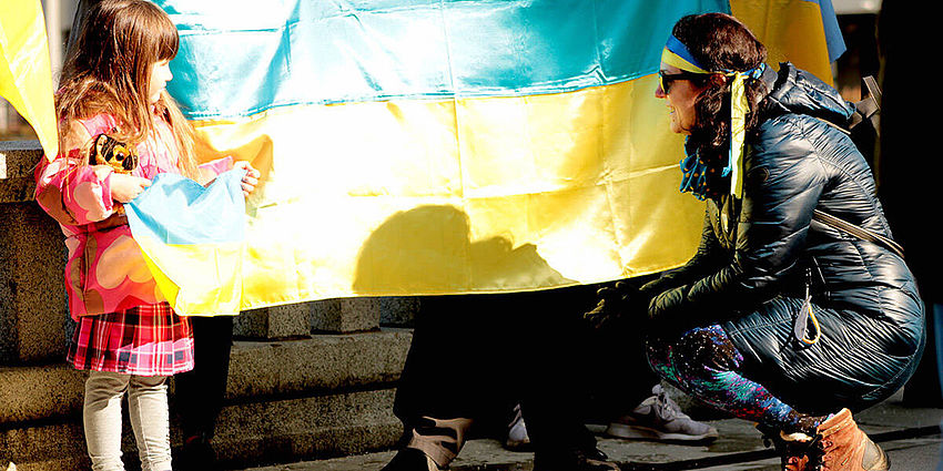 young girl and a woman stand with flag of Ukraine